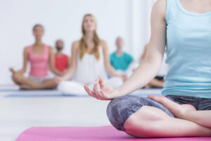 Closeup shot of a woman in sportswear sitting on a pink mat and doing yoga